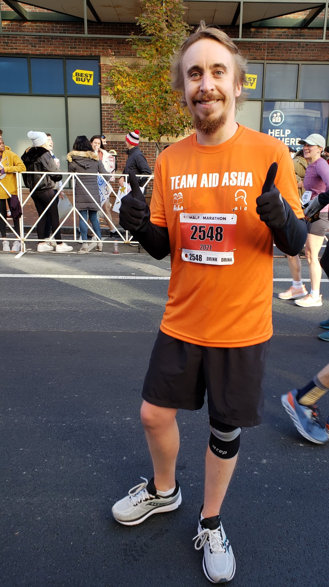 Runner holding thermal blanket overhead with medal